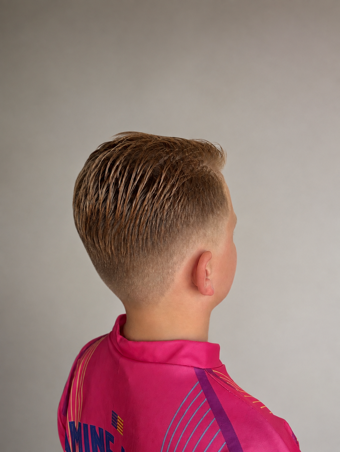Kort jongenskapsel met een fade aan de zijkant, van opzij gezien