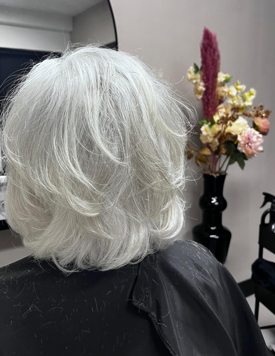 Zilvergrijs haar, kort in laagjes geknipt, van achteren gezien in de salon